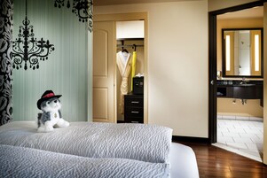 A hotel room with a bed, a wardrobe, a bathroom with a sink and mirror, and a small decorative item on the bed.