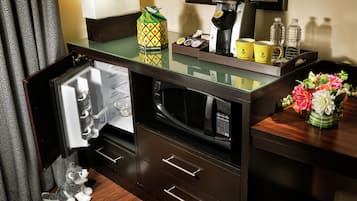 A compact kitchen area with a microwave, coffee maker, and a small refrigerator.