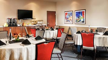 Una zona de dinar d'hotel amb diverses taules i cadires, un racó de cafè i obra d'art a les parets.