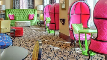 A room with a green sofa, pink chairs, and a patterned carpet.