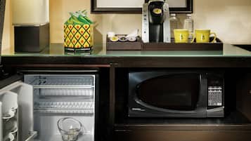 Cocina compacta con microondas, refrigerador y cafetera.