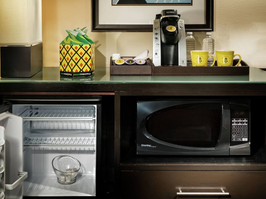 Cocina compacta con microondas, refrigerador y cafetera.