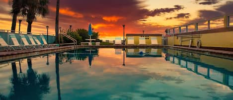 Una piscina al aire libre, sombrillas, sillones reclinables de piscina