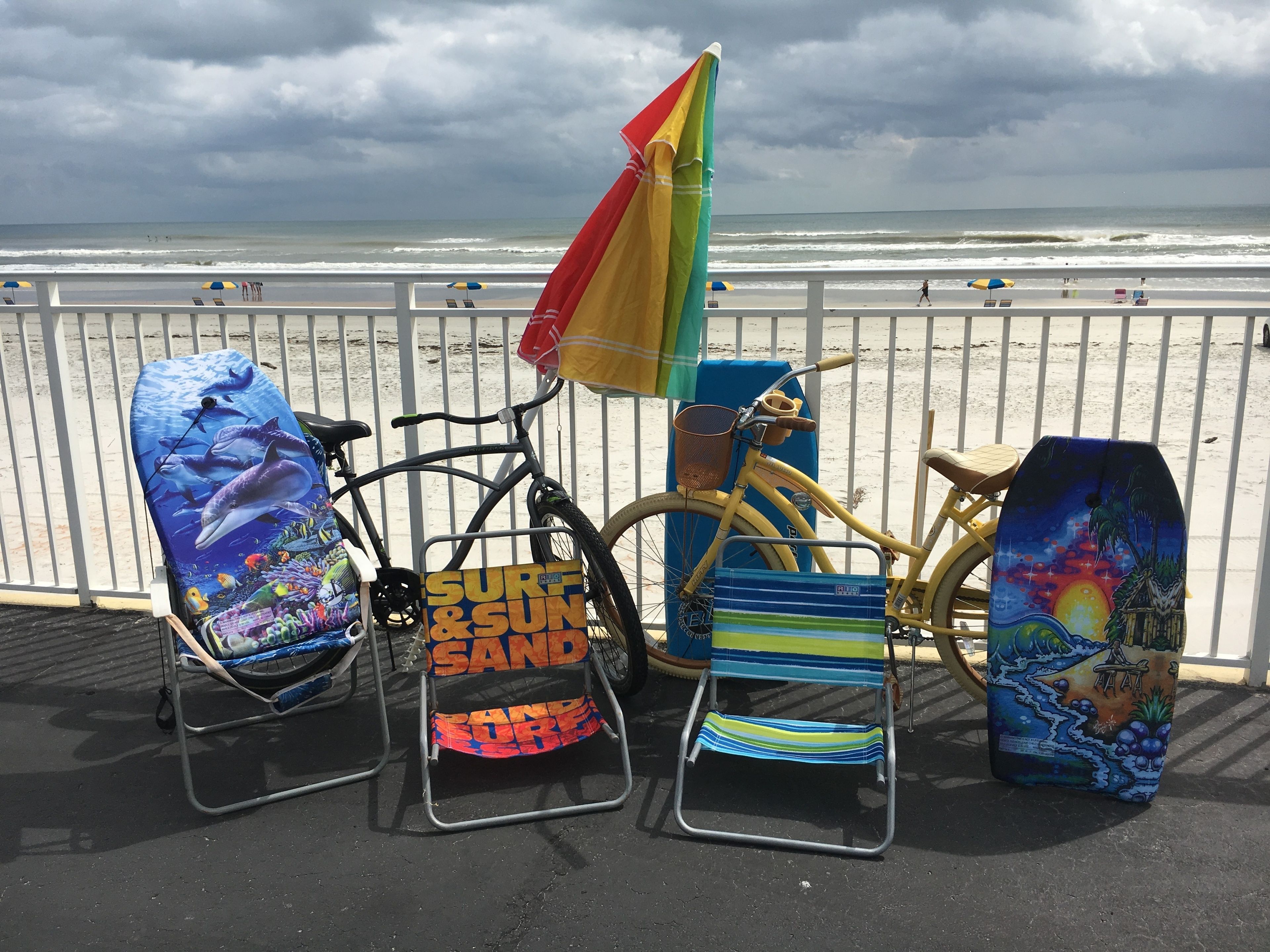 Beach chairs and a bicycle on a promenade with a view of the ocean.