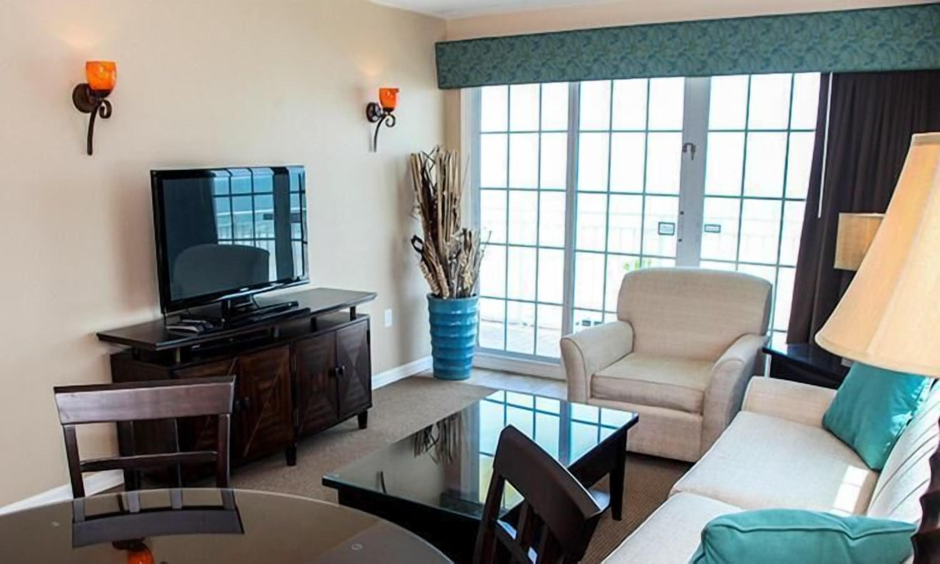 Una sala de estar con televisor, sofá, mesa de centro y una silla.