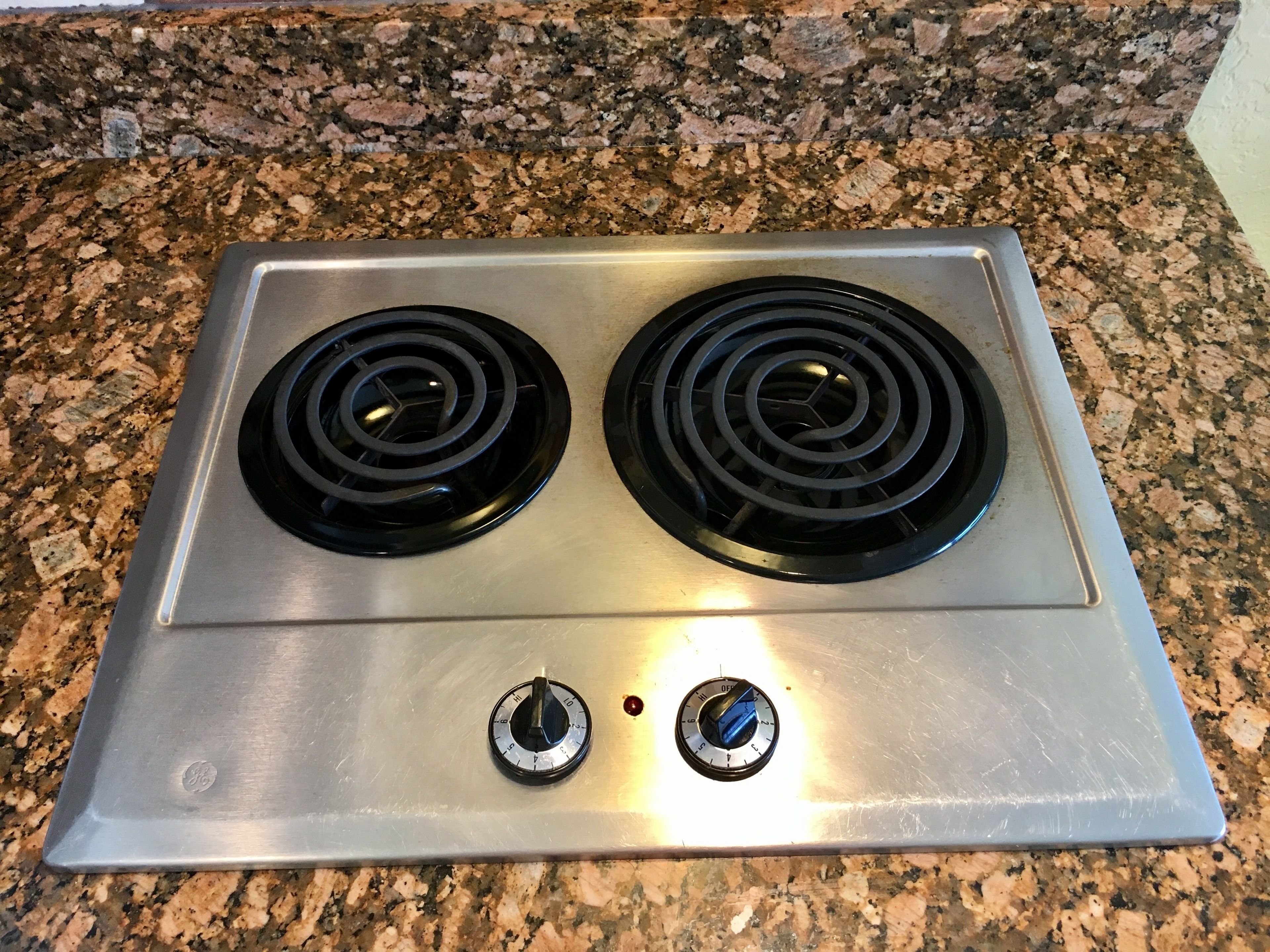 A stainless steel stove with two burners and two knobs.