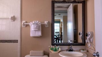 Baño con inodoro, lavamanos, espejo, toallero y artículos de aseo.