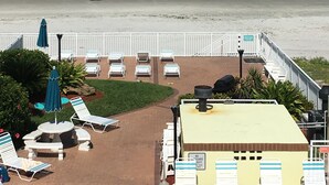 Vista de una playa desde un resort, con sillas de descanso, sombrillas y una torre de salvavidas.