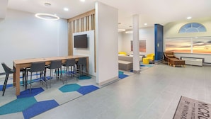 A modern conference room with a long table, chairs, a flat-screen TV, and a colorful abstract rug. - Microtel Inn & Suites by Wyndham Opelika (Opelika)