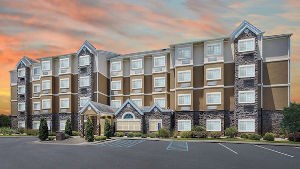 A multi-story hotel with a stone facade, multiple windows, and a parking lot. - Microtel Inn & Suites by Wyndham Opelika (Opelika)