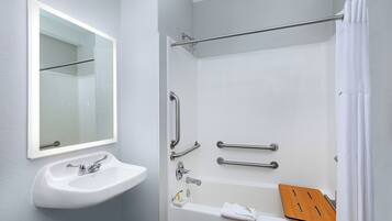 A bathroom with a white sink, mirror, and bathtub.