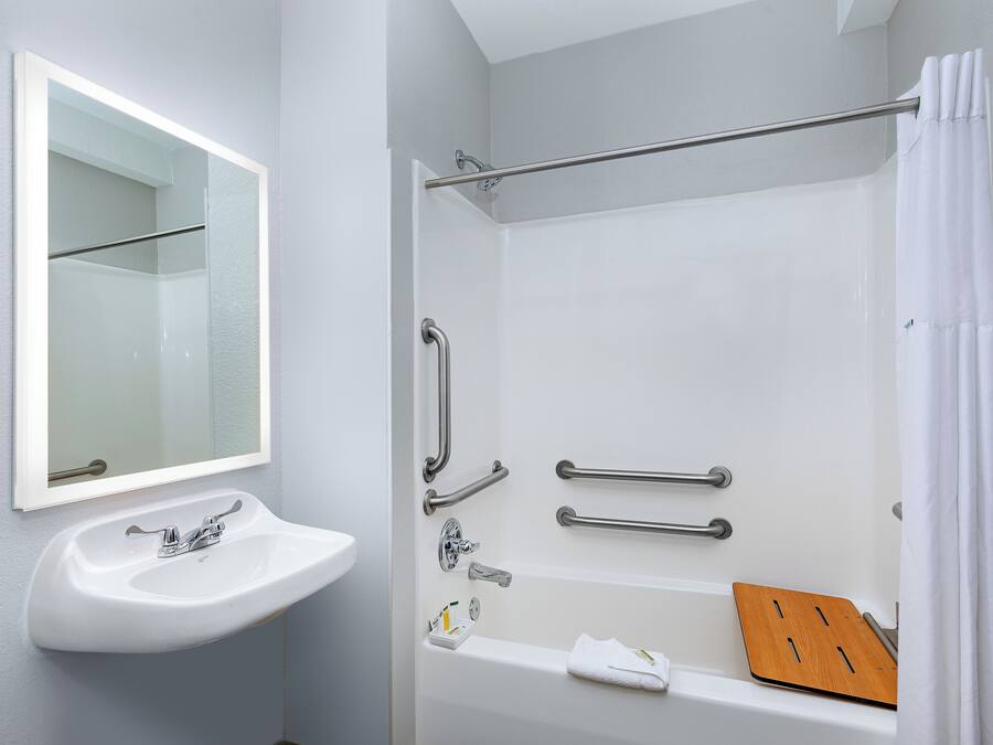 A bathroom with a white sink, mirror, and bathtub.
