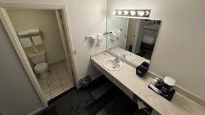 Uma casa de banho de hotel com lavatório, espelho e toucador.