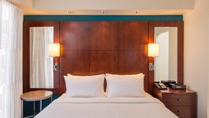 A hotel room with a large bed, two bedside lamps, a small round table, a dresser, and a mirror. - Residence Inn by Marriott Pittsburgh North Shore (Pittsburgh)