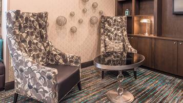Una habitación con dos sillones estampados, una mesita redonda y una lámpara de pared.