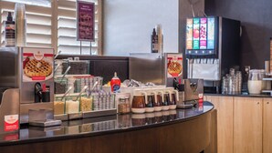 A breakfast bar with waffle options, syrup dispensers, and a TV screen displaying menu items. - Residence Inn by Marriott Pittsburgh North Shore (Pittsburgh)