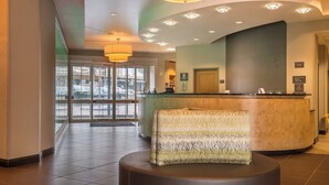 A hotel reception area with a curved counter, a patterned ottoman, and a large window providing a view of the outside. - Residence Inn by Marriott Pittsburgh North Shore (Pittsburgh)