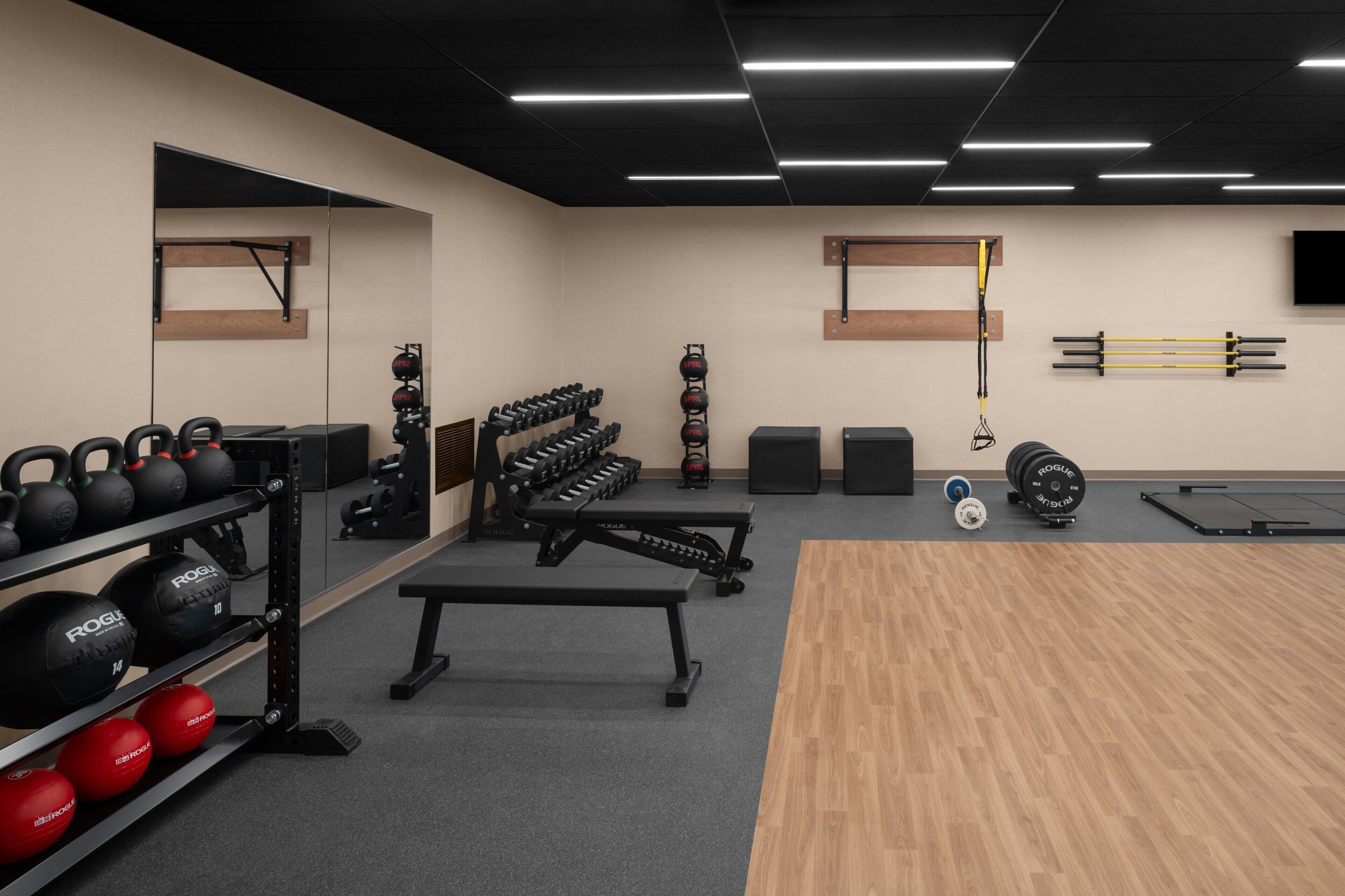 A gym with kettlebells, dumbbells, a bench, and a pull-up bar.
