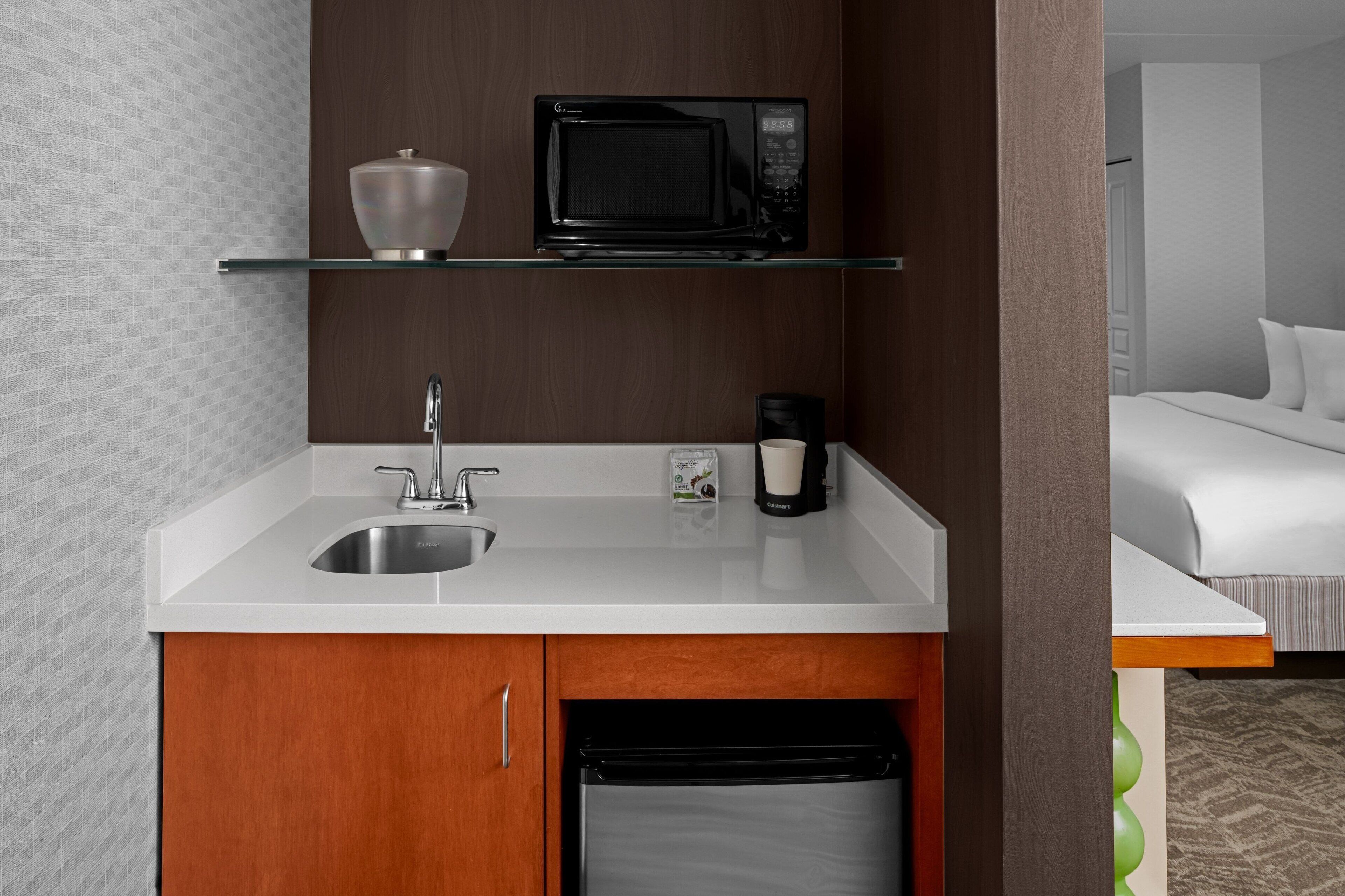 A compact kitchenette with a microwave, coffee maker, and a small sink.