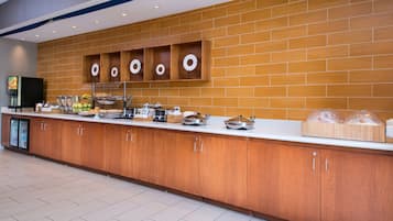 A buffet area with a long counter, wooden cabinets, and various food items.