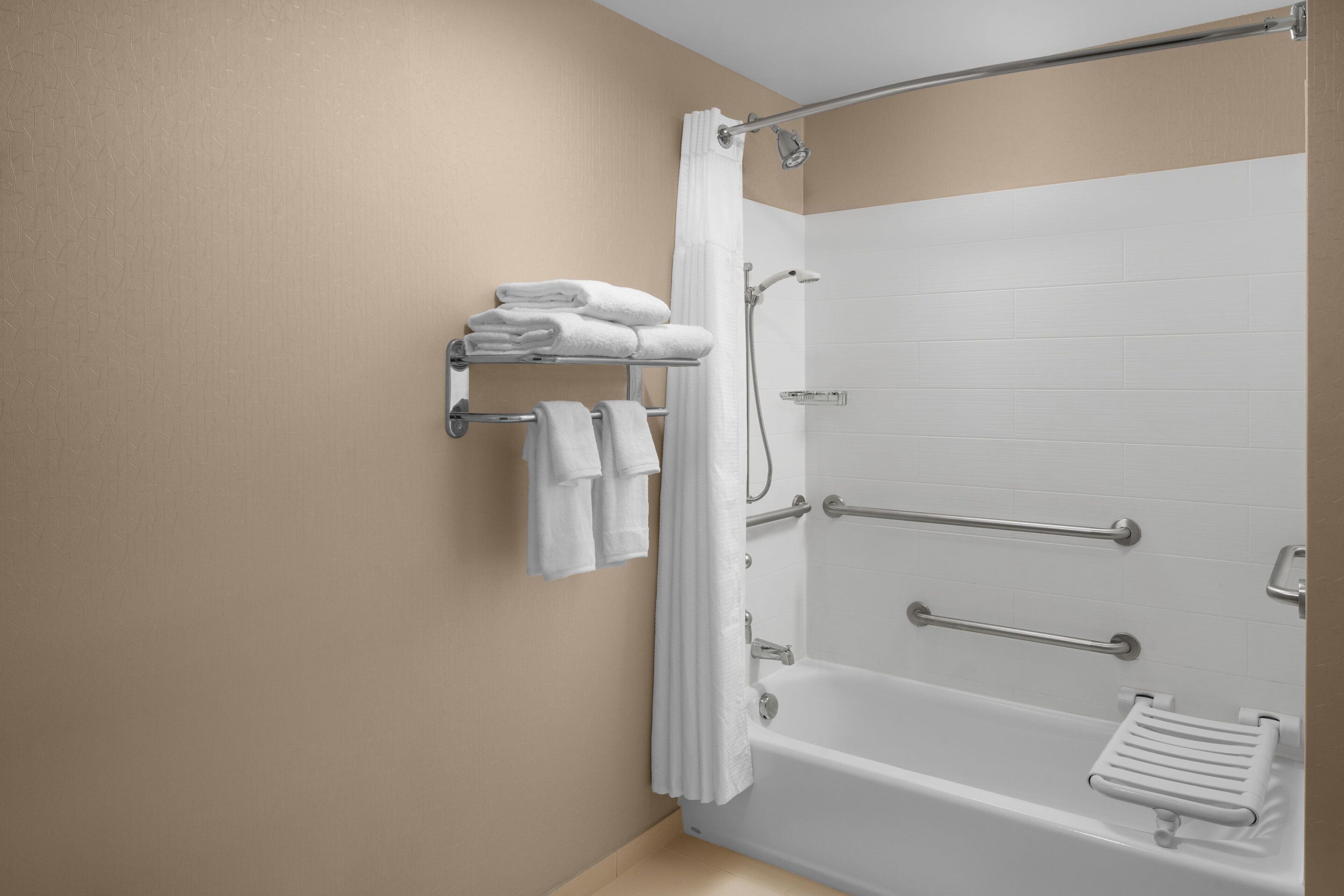 A bathroom with a bathtub, a shower, and a towel rack with folded towels.
