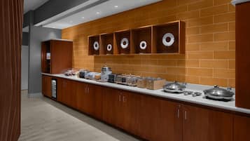 Una cocina moderna con armarios de madera, una encimera con varios electrodomésticos y una pared de ladrillo.