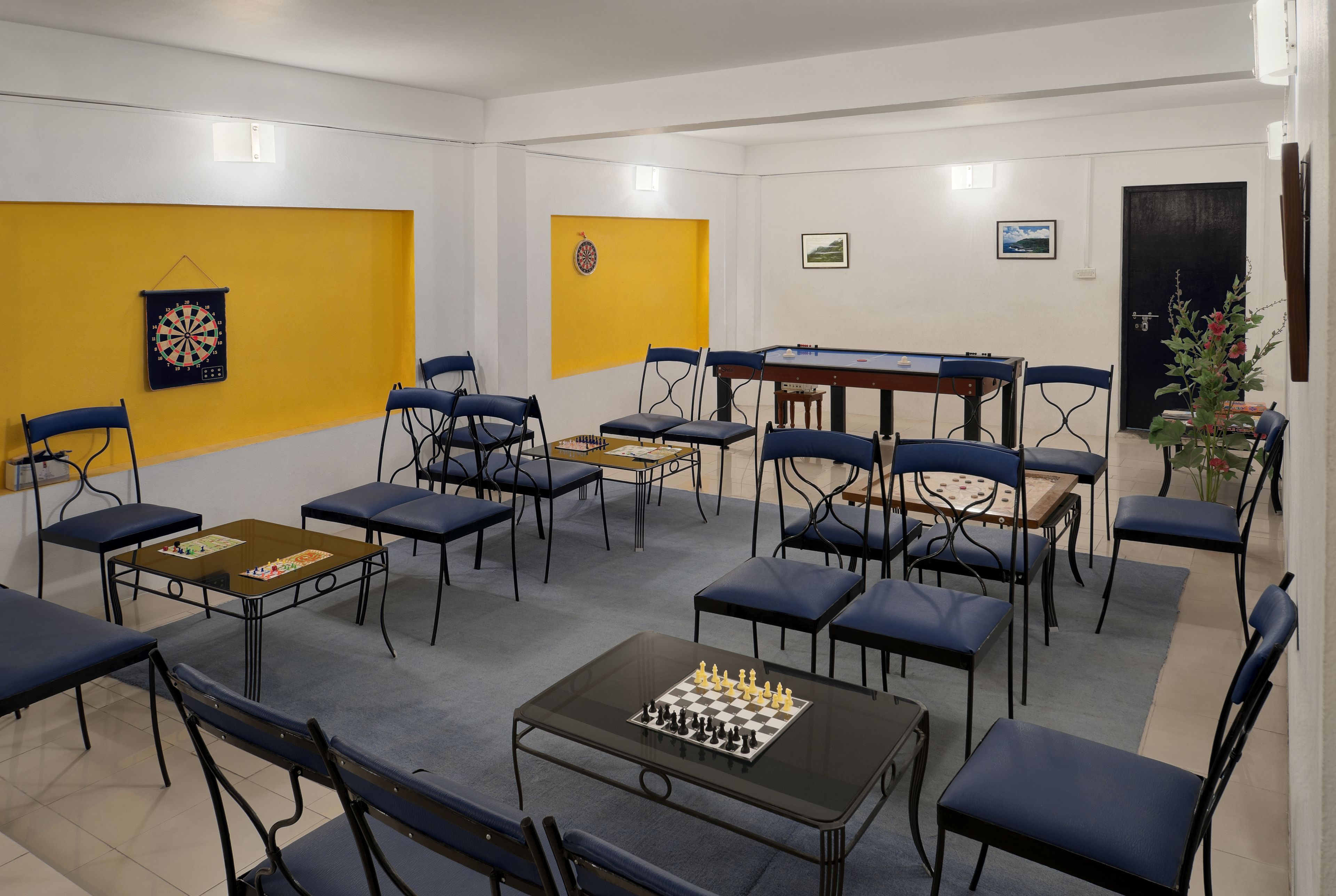 A room with a dartboard, chessboard, and multiple tables and chairs.