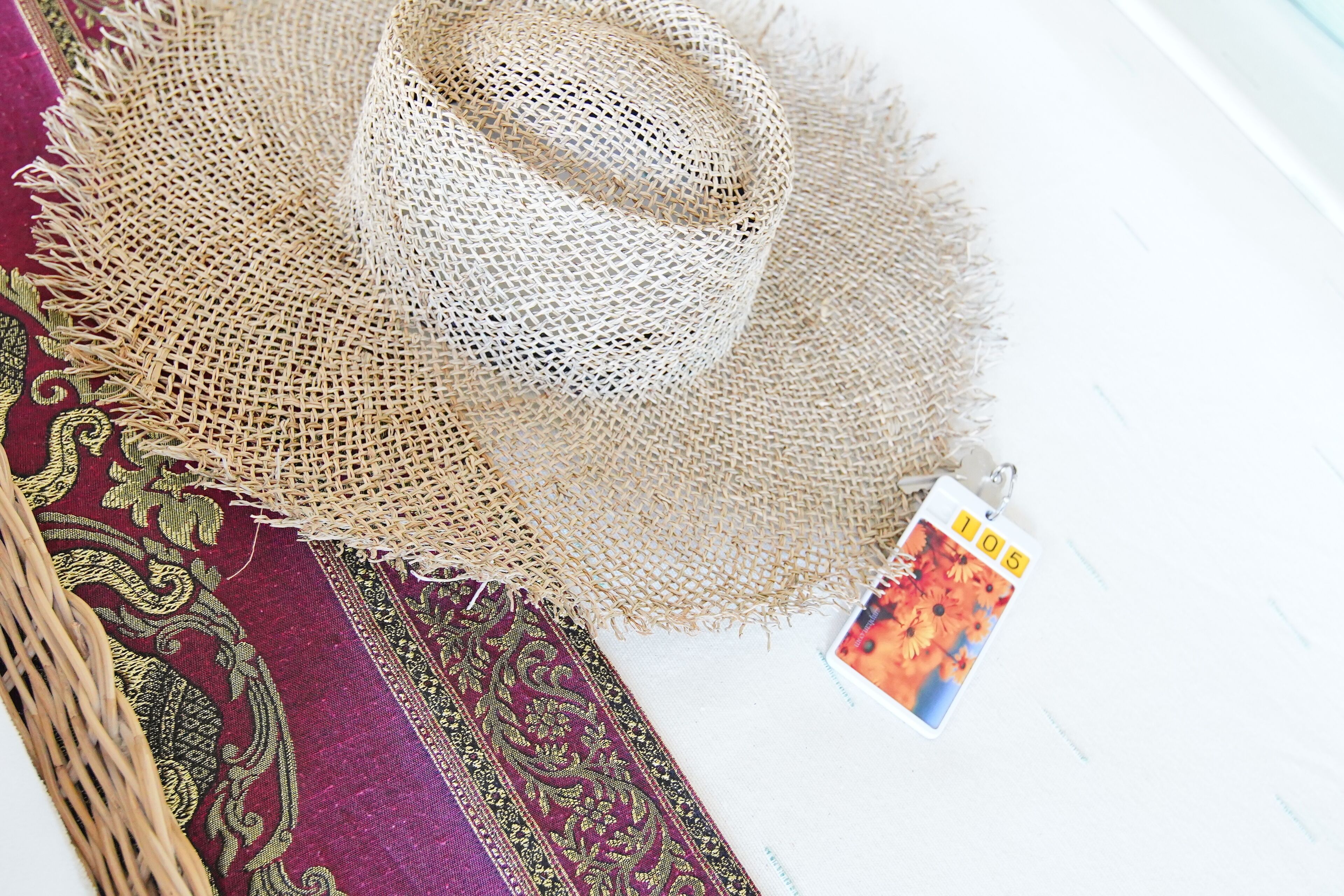 Un chapeau de paille, un panier tressé et un tissu à motifs.