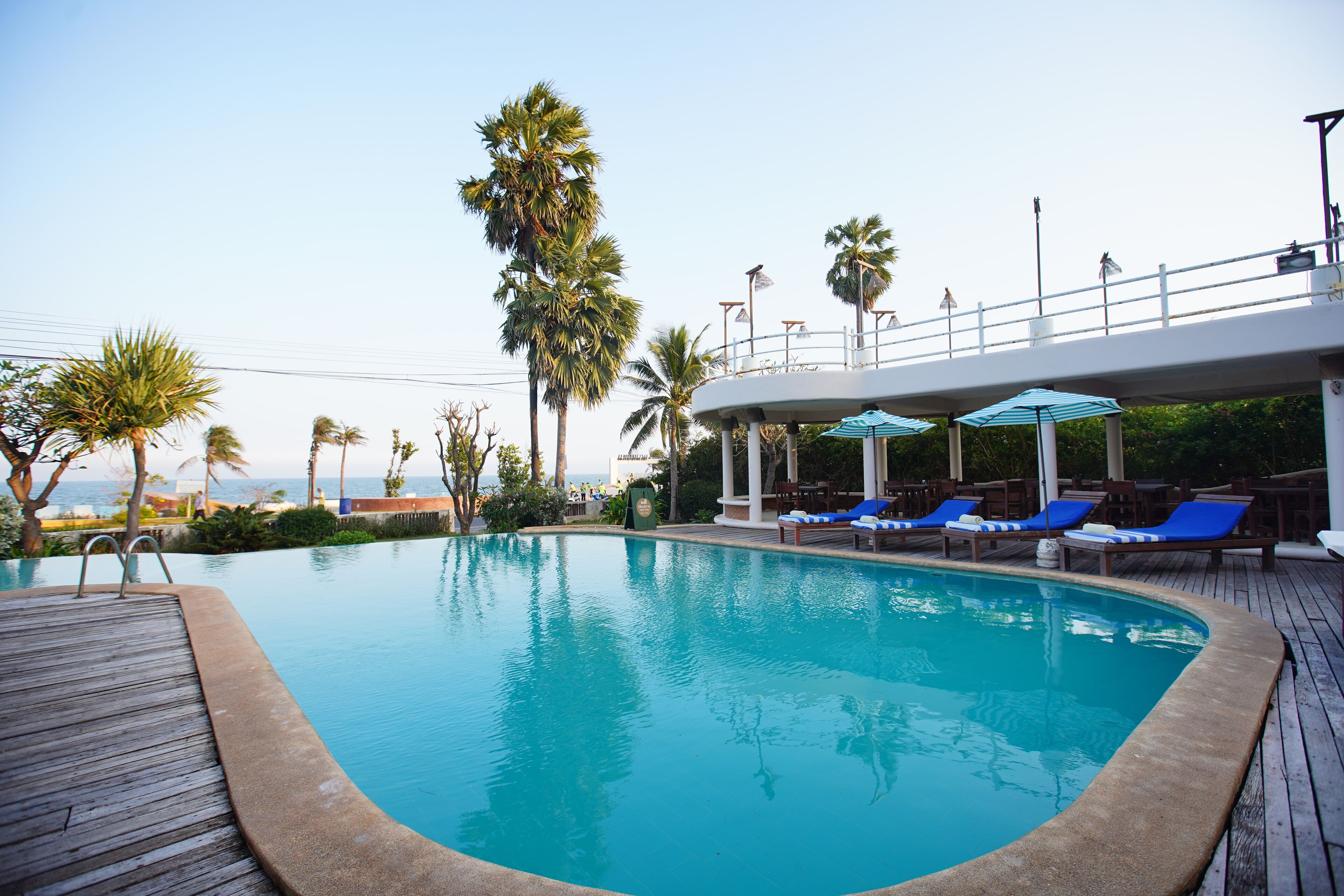 A swimming pool with a wooden deck, lounge chairs, and umbrellas.