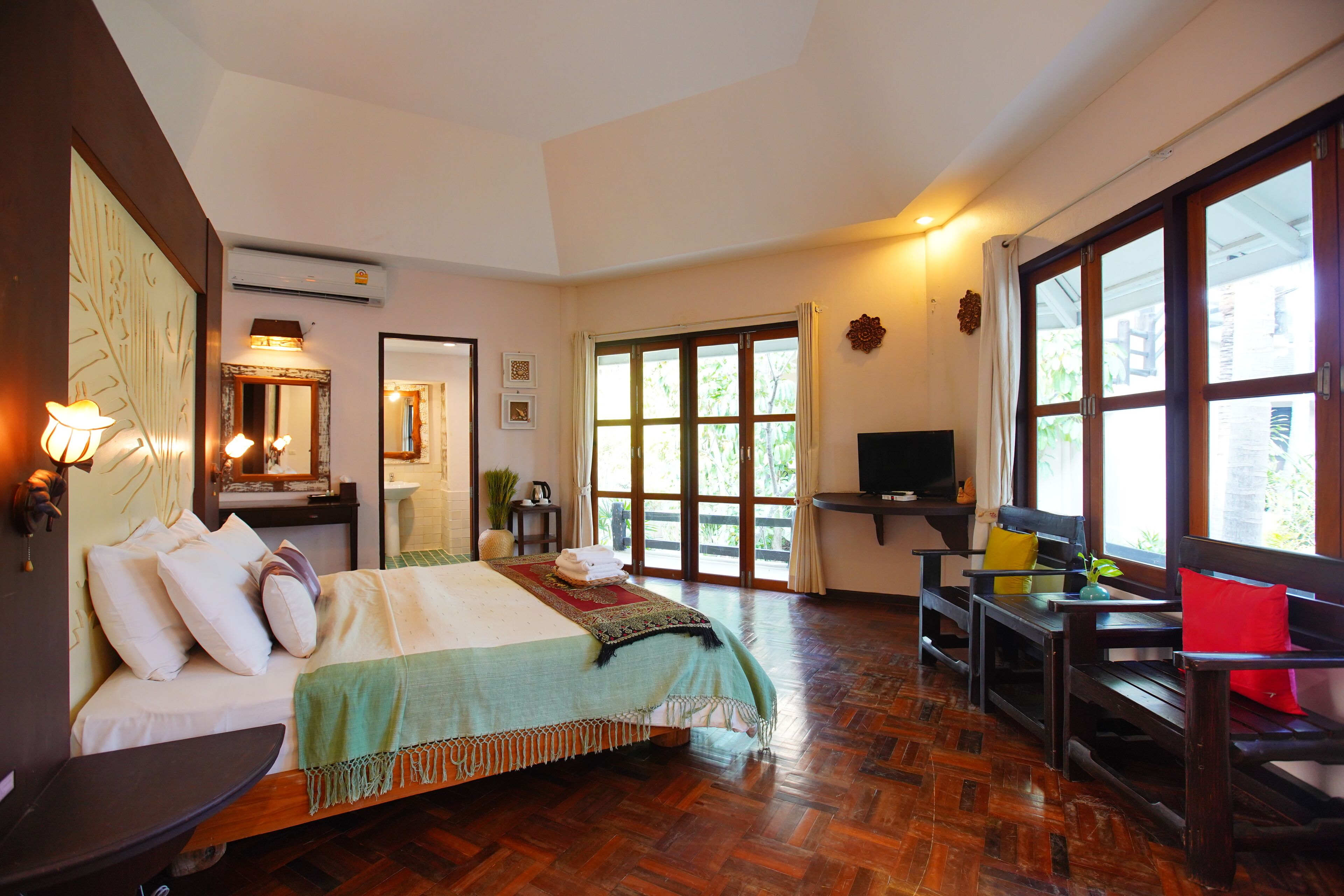 A spacious room with a large bed, a TV, and a seating area with a view of the outdoors.