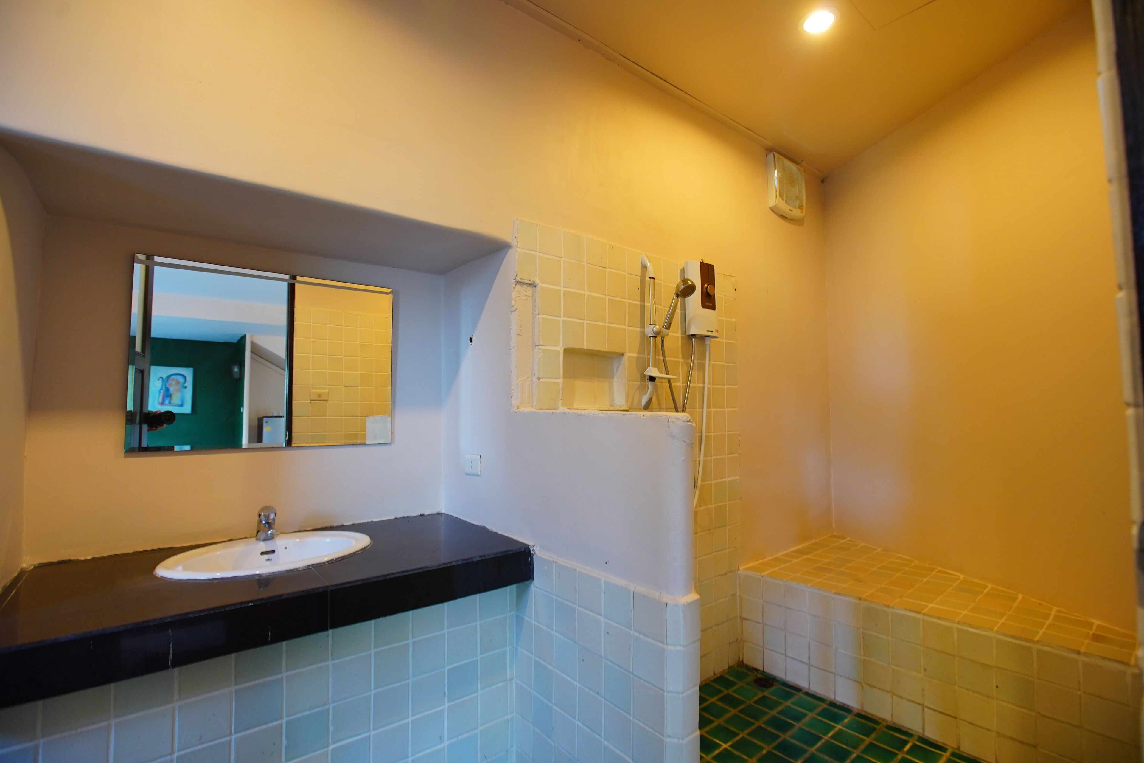 A bathroom with a sink, mirror, shower, and tiled floor.