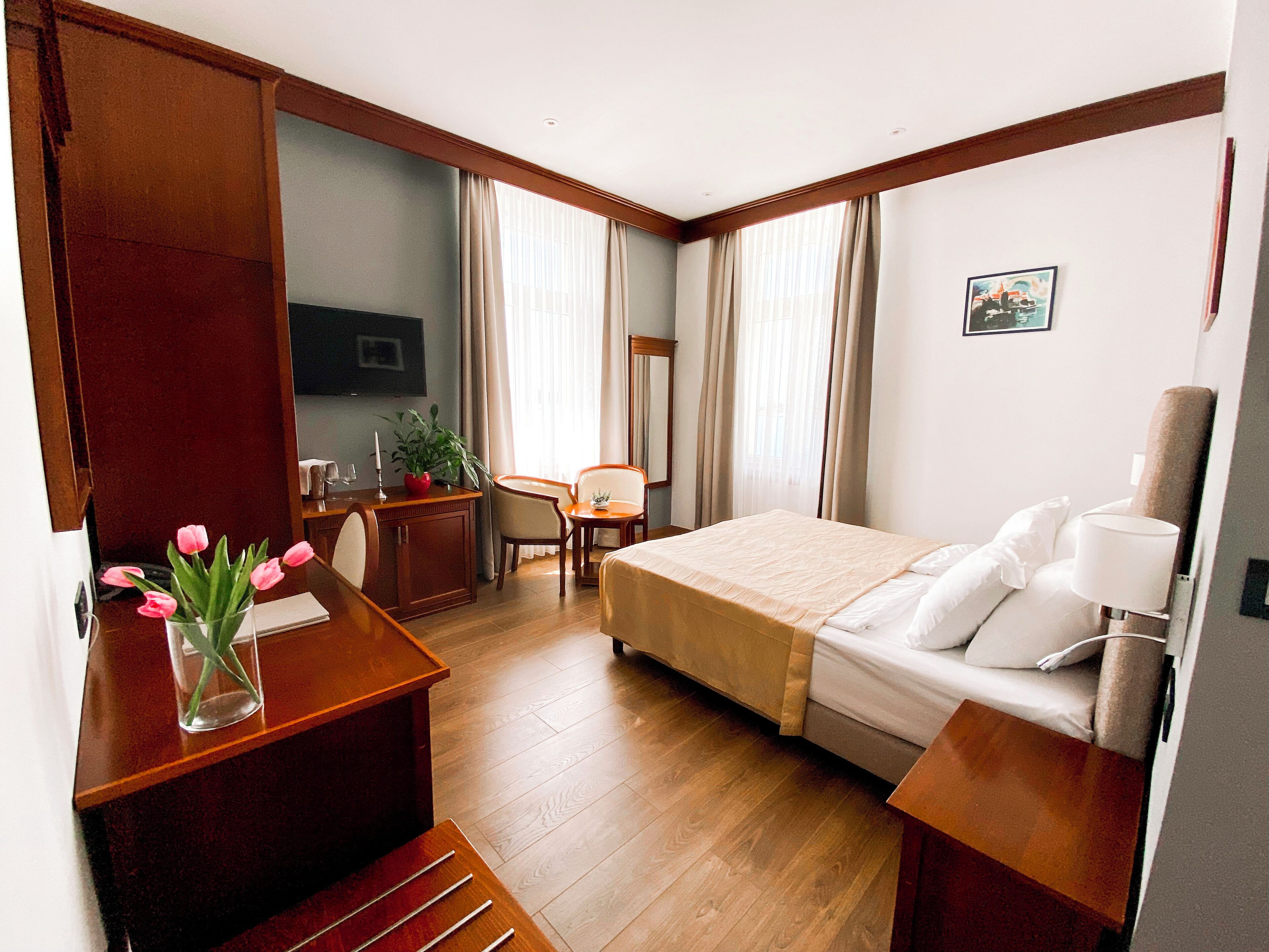 Une chambre d’hôtel comprenant un lit, une table de chevet, un bureau, une chaise et une petite table avec une plante.