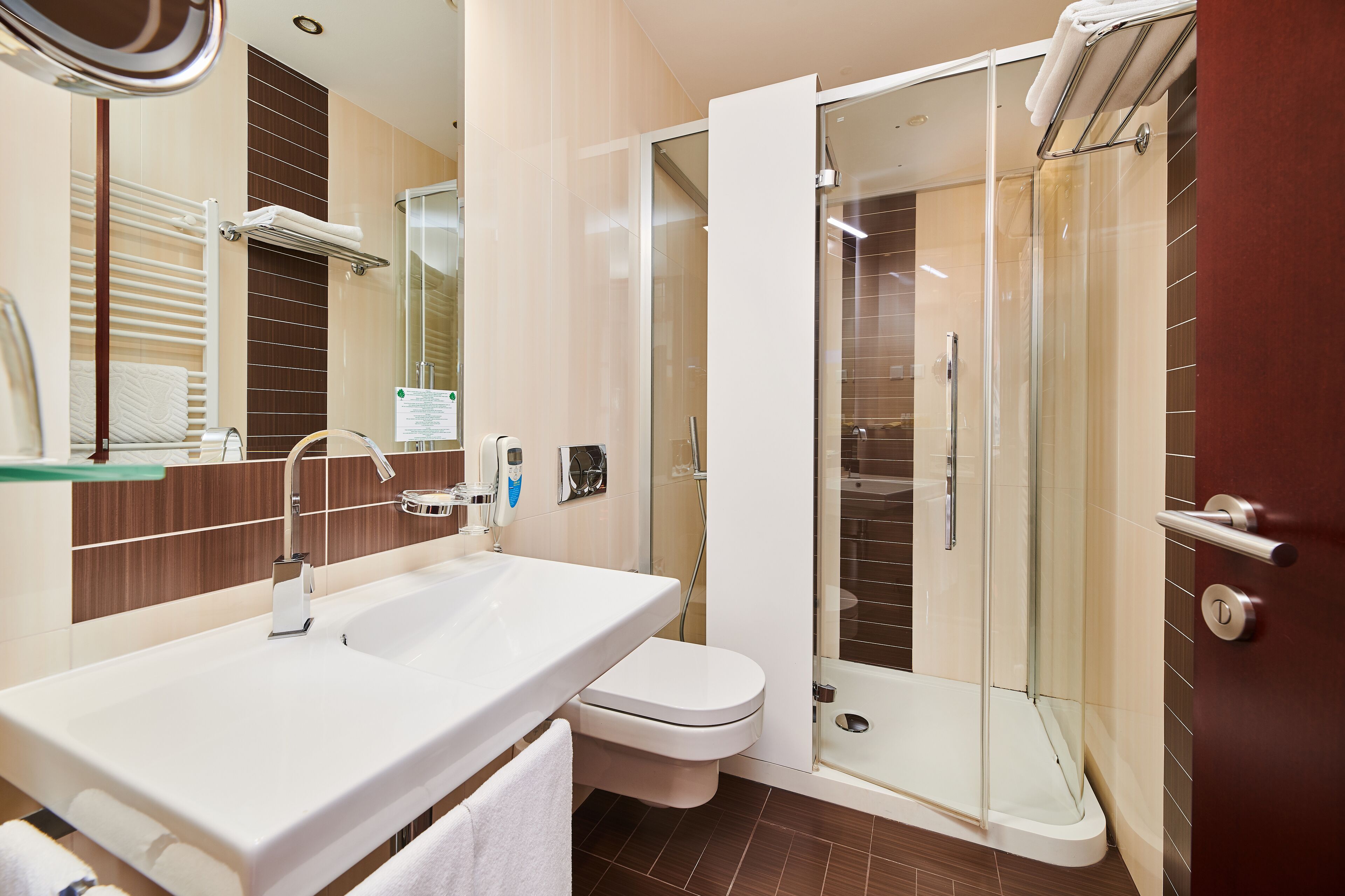 A modern bathroom with a white sink, toilet, and glass-enclosed shower.
