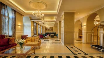 A spacious lobby with a grand chandelier, plush seating, and a clean, polished floor.