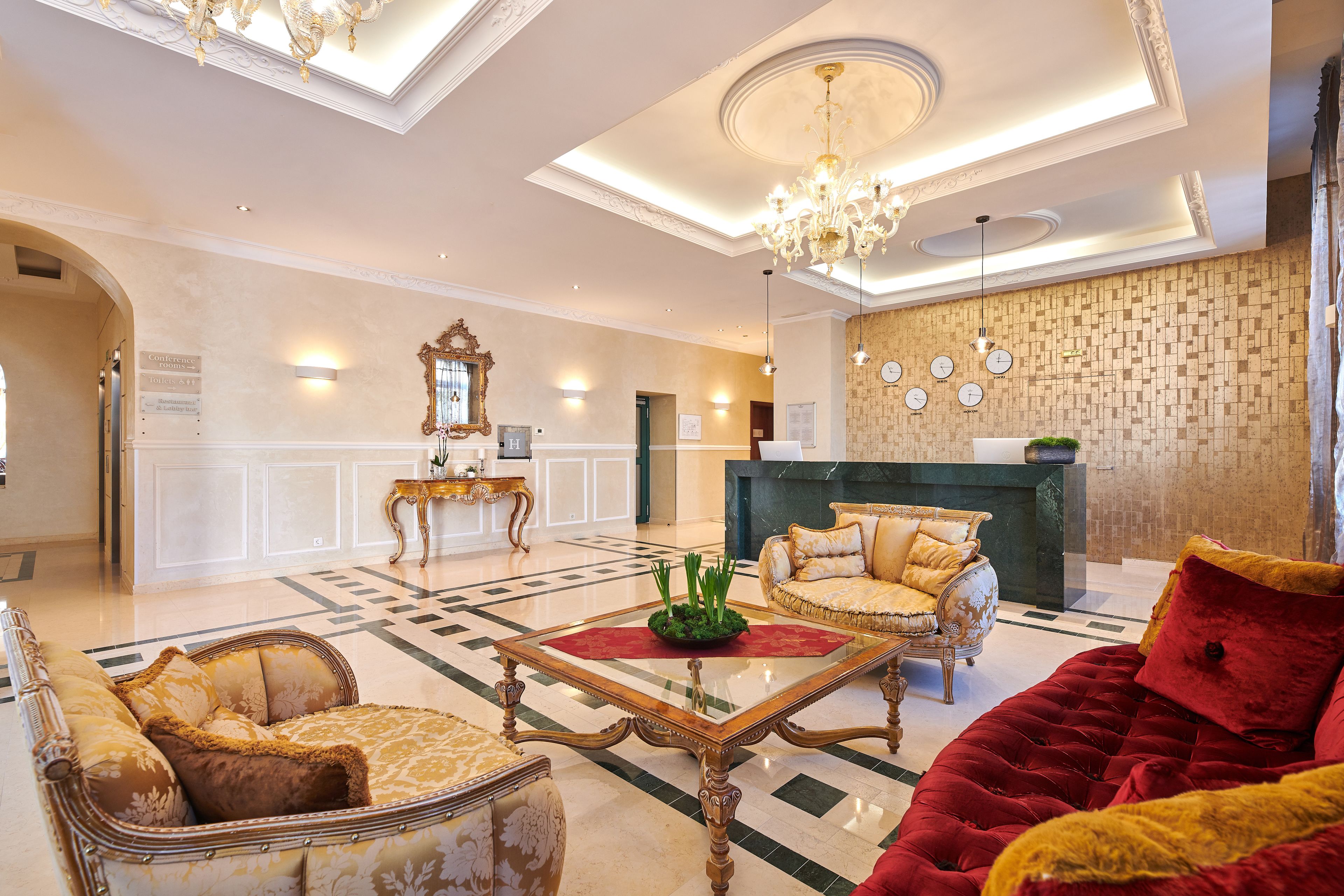 A spacious lobby with a grand chandelier, a reception desk, and classic furniture.