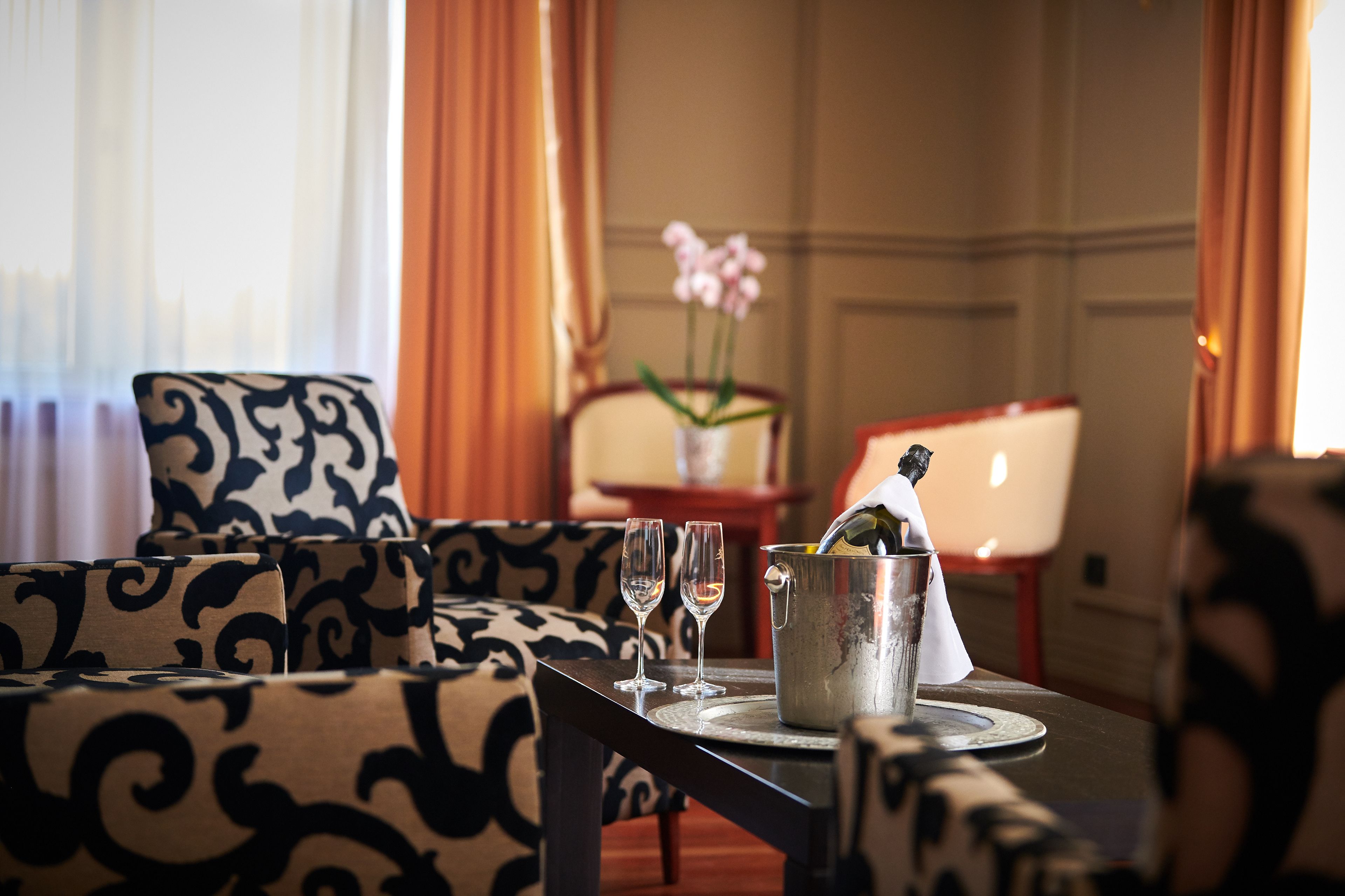 Habitación de hotel con una mesa de comedor servida con dos copas de vino y una botella de champán en un cubo de metal.