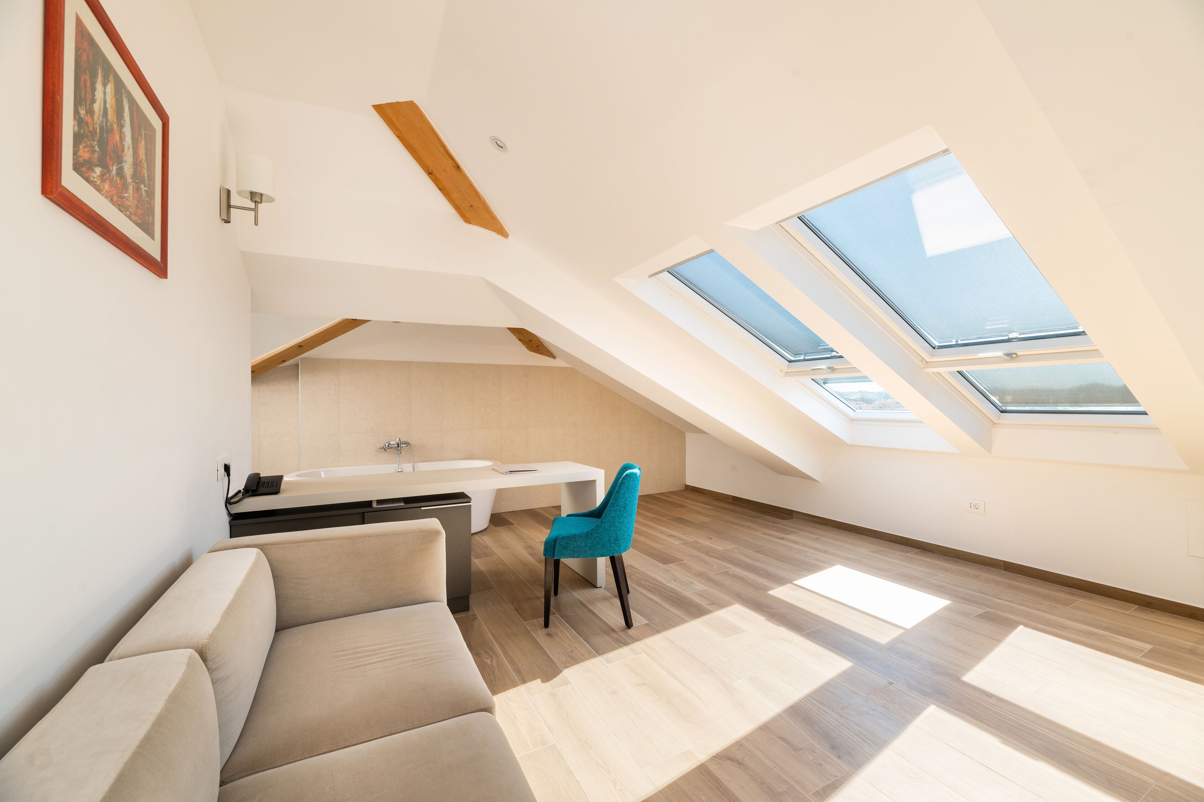 A modern loft bedroom with skylights, a sofa, and a chair.