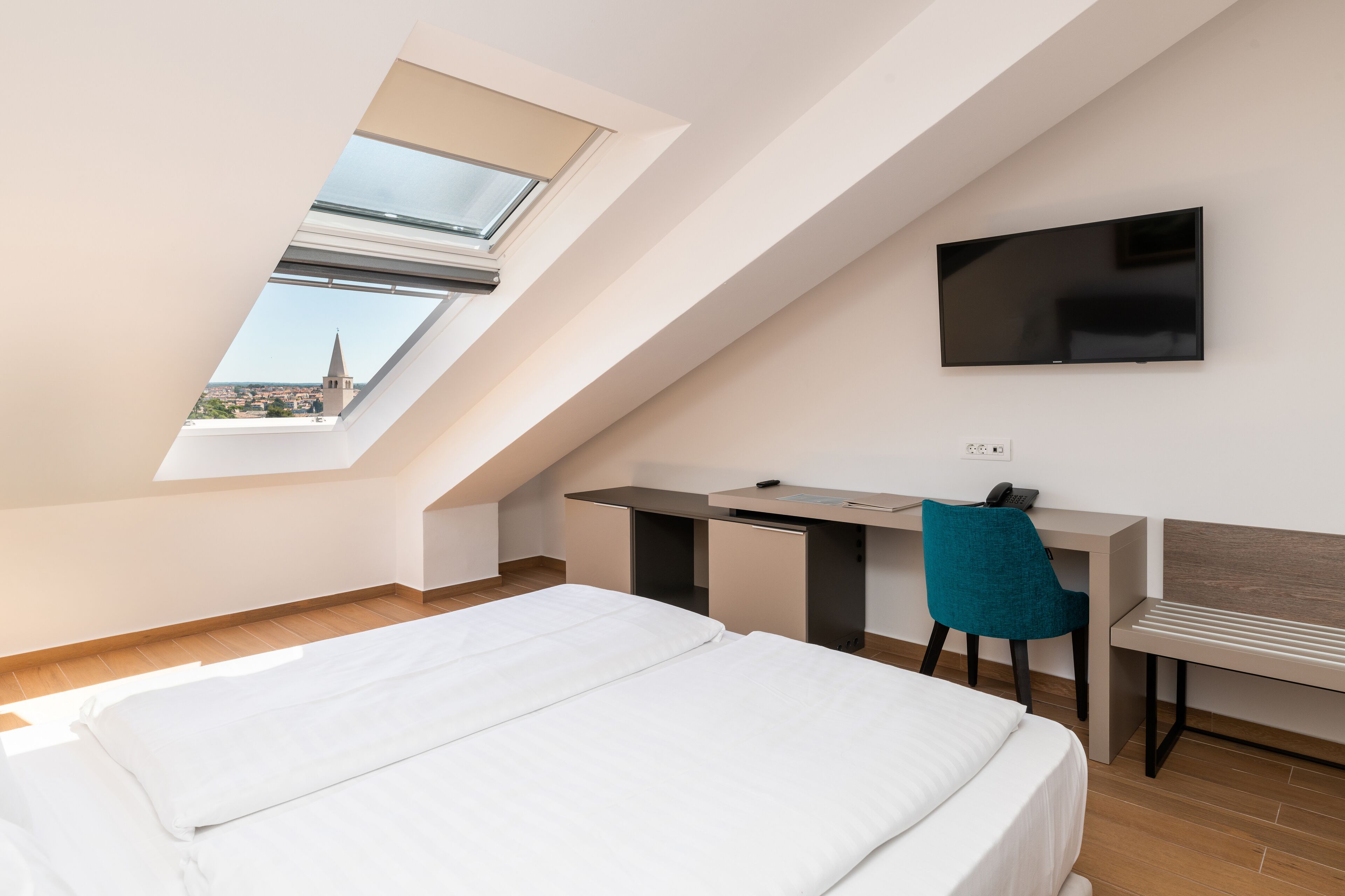 Una habitación de hotel moderna con tragaluz, una cama, un escritorio y un televisor.