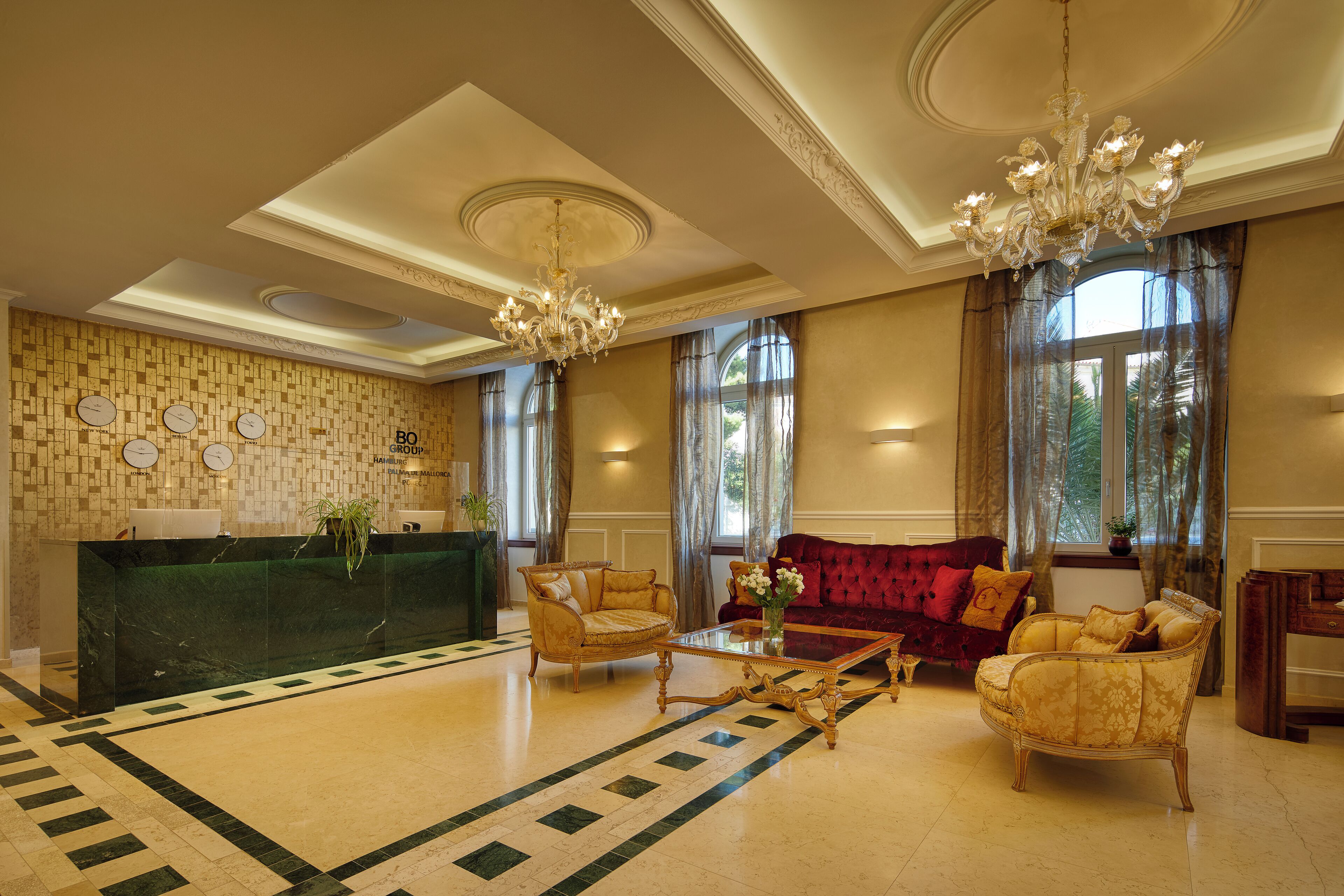 Eine Lobby mit einer Rezeption, zwei Sofas, einem Couchtisch und einem Kronleuchter.