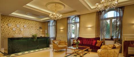 Eine Lobby mit einer Rezeption, zwei Sofas, einem Couchtisch und einem Kronleuchter.