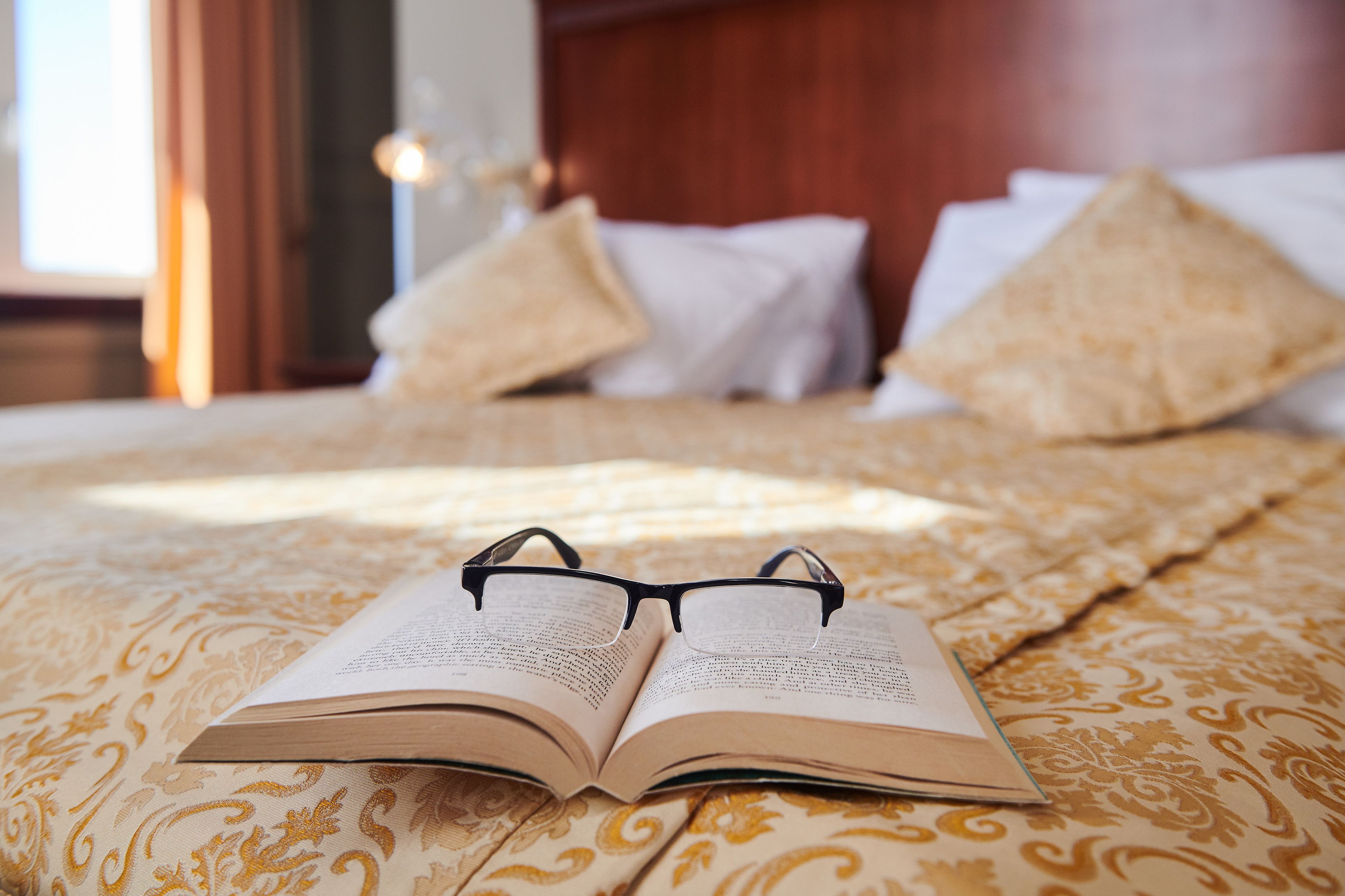Een open boek op een bed met een beddengoed met dessin.