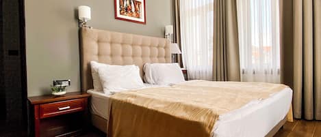 A hotel room with a large bed, a nightstand, a framed picture on the wall, and a window with curtains.