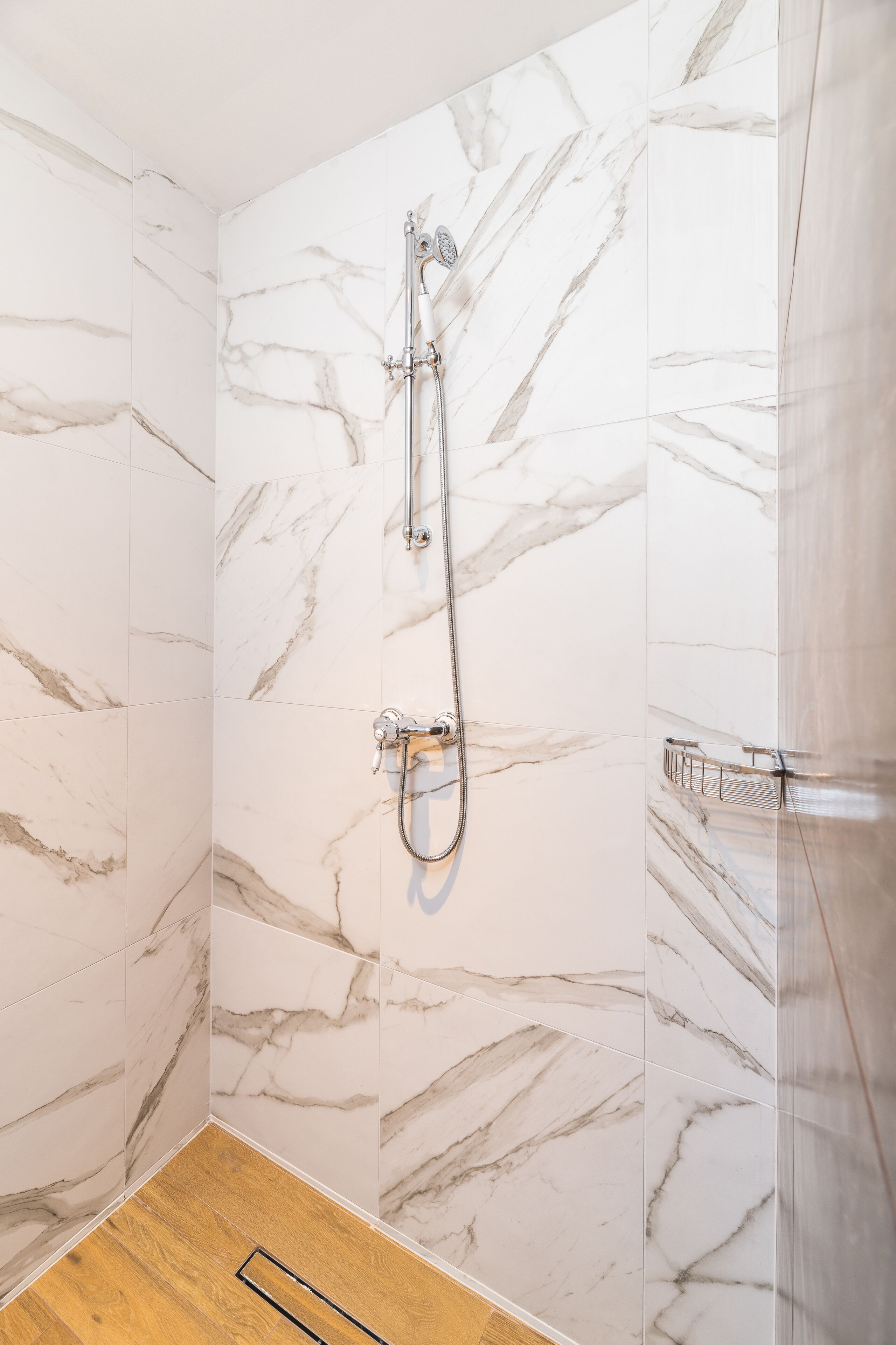 A bathroom with marble walls and a shower.