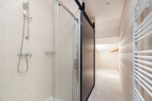 A modern bathroom with a glass shower enclosure, a towel rack, and a visible toilet.