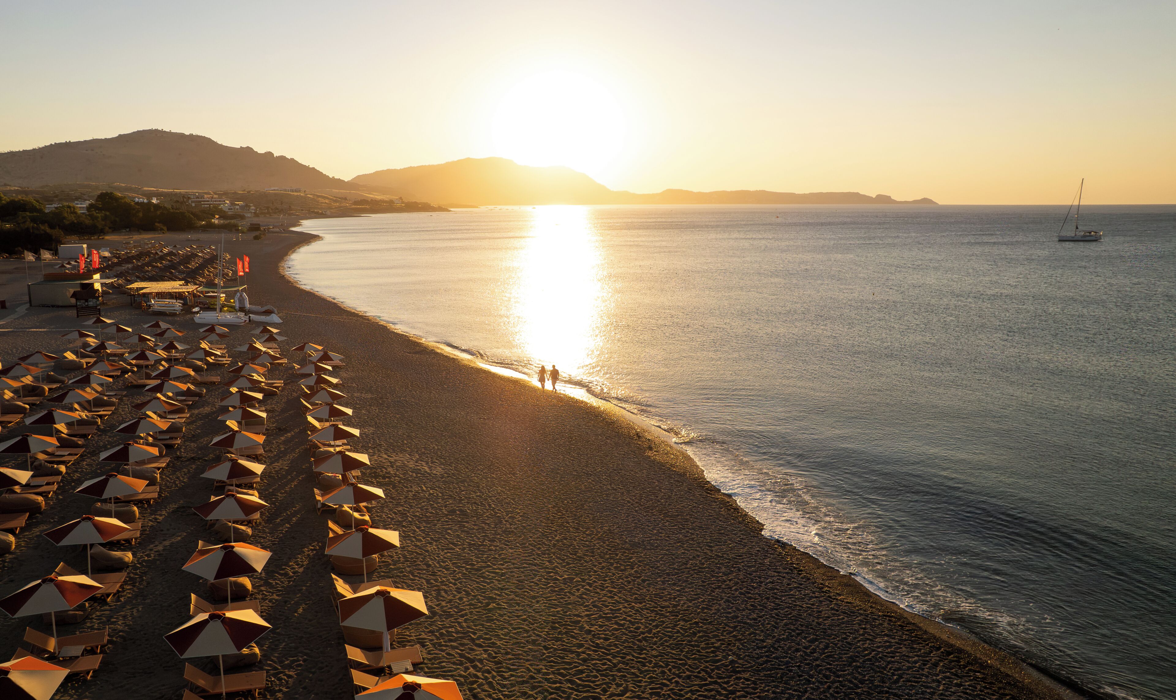 Una playa con hileras de sombrillas y una vista despejada del mar.