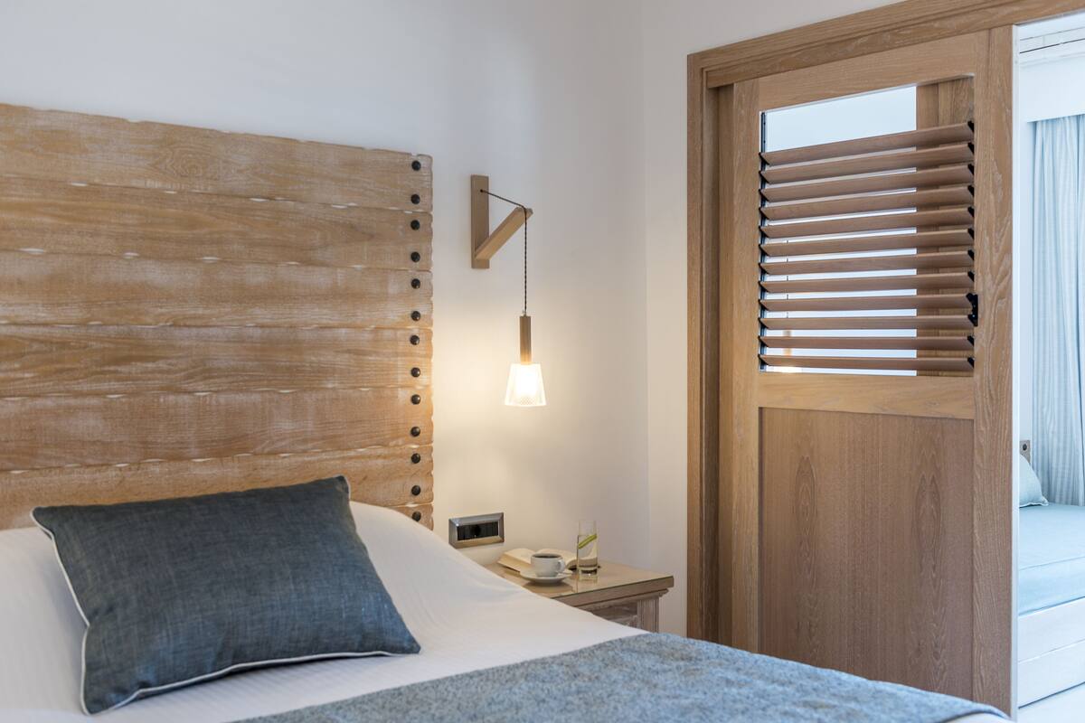 A neatly made bed with a pillow, a bedside table with a lamp, and a wooden headboard.