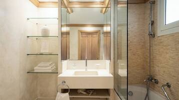 Un baño moderno con cabina de ducha de vidrio, tocador con espejo y perchero.