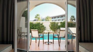 Habitación con puerta de vidrio que da a una zona de piscina, con una mesa y sillas y vistas a la piscina.