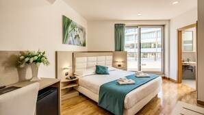 Una habitación de hotel moderna con una cama grande, mesitas de noche, un escritorio y vistas al exterior.