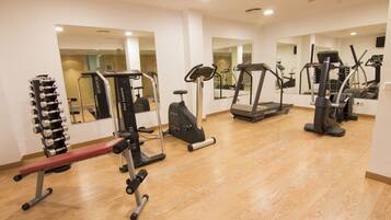Une salle de sport moderne équipée de divers appareils d’exercice, notamment des tapis de course et des appareils de musculation, et dotée de grands miroirs sur les murs.